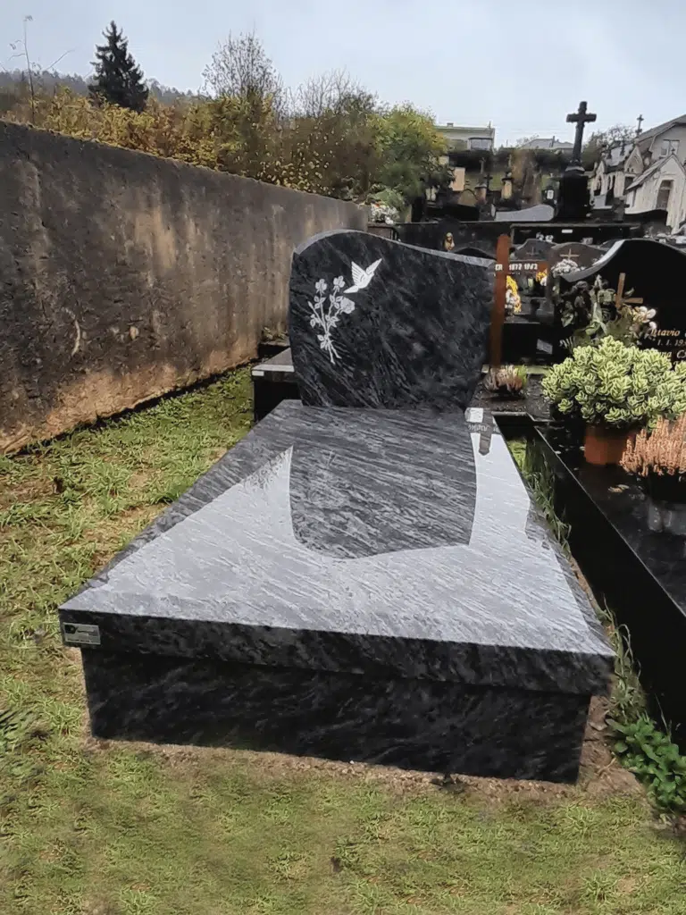 Tombe moderne en granit bleu avec gravures décoratives de roses et de colombe.