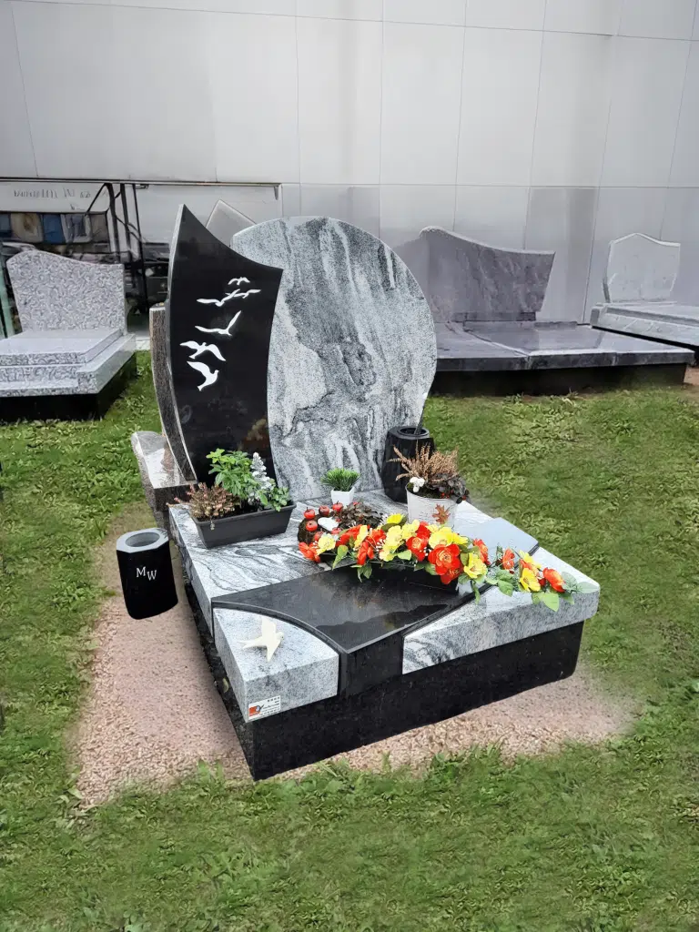 Monument cinéraire contemporain bicolore avec stèle noire gravée d'oiseaux et fleurs.