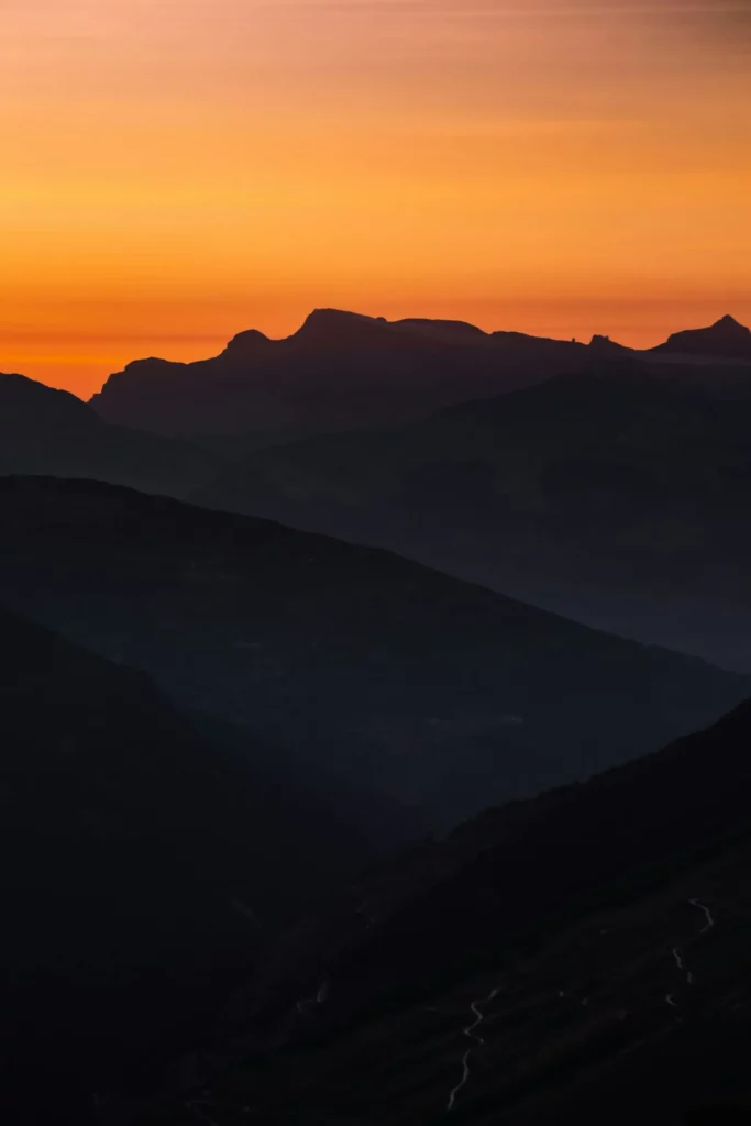 Paysage de montagnes sombres sous un ciel d'oraison au crépuscule.