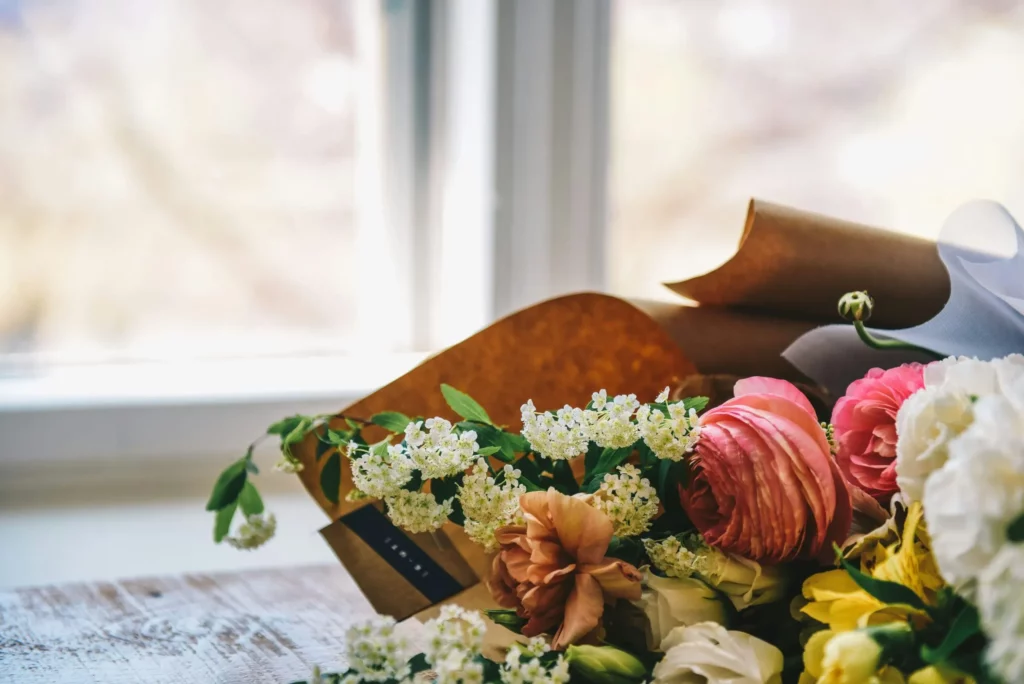 Bouquet de fleurs de deuil fraîches posé sur un meuble en bois clair.
